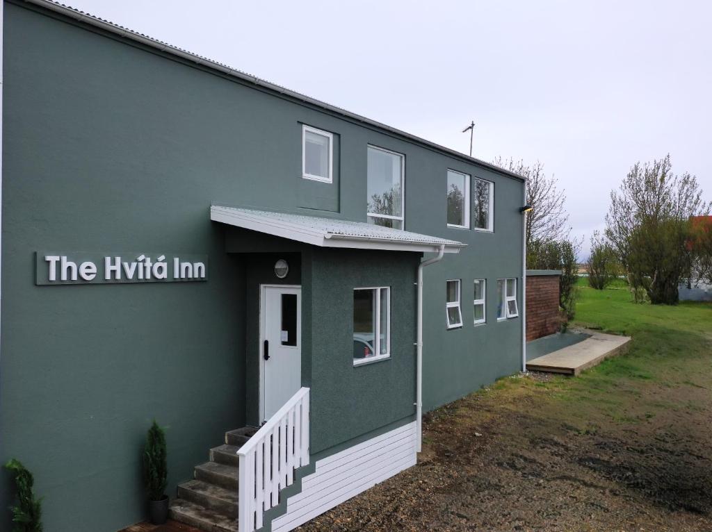 une maison verte avec l'auberge hybride écrite sur elle dans l'établissement The Hvítá Inn, à Bær