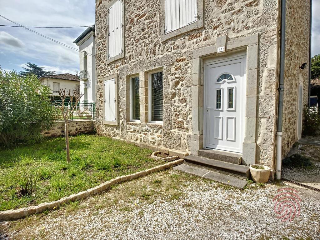 une maison en pierre avec une porte blanche et une cour dans l'établissement Charmante maison F4 avec terrasse proche Thermes et centre, animaux acceptés - FR-1-451-210, à Lamalou-les-Bains
