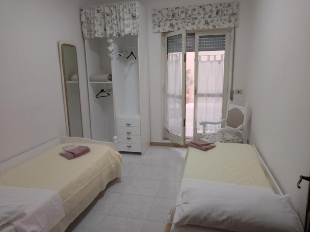 um quarto branco com 2 camas e uma janela em Orchidea1 em Marcianise
