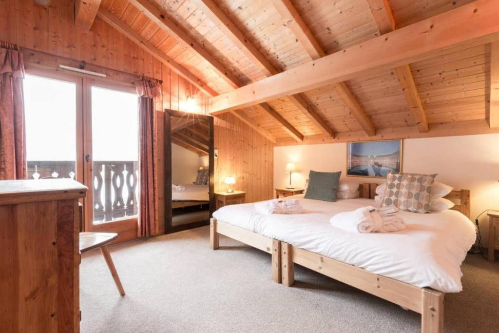 a bedroom with a large bed and a large window at Chalet Ruan Montriond - Mountain Voyages in Montriond
