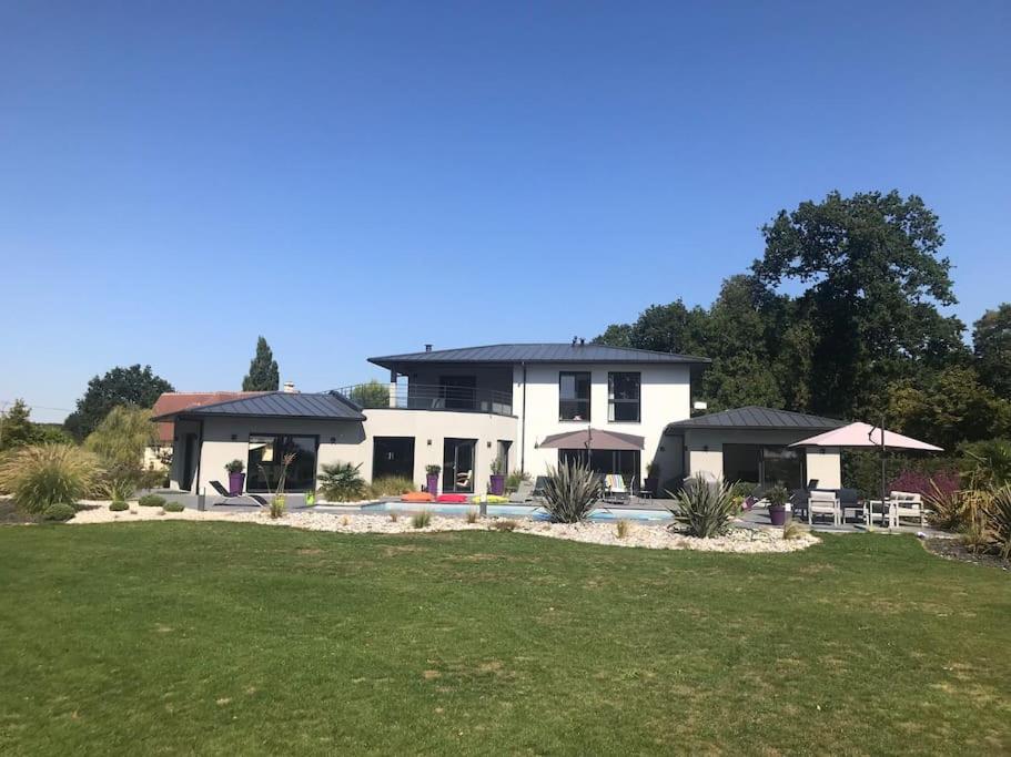 une grande maison blanche avec une cour et de l'herbe dans l'établissement Villa avec piscine, à Janville
