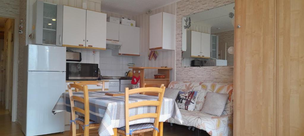 une cuisine avec une table, des chaises et un réfrigérateur dans l'établissement Appartement à GOURETTE, résidence EURONEIGE, avec balcon, vue idéale sur la montagne - 6 personnes, à Eaux-Bonnes