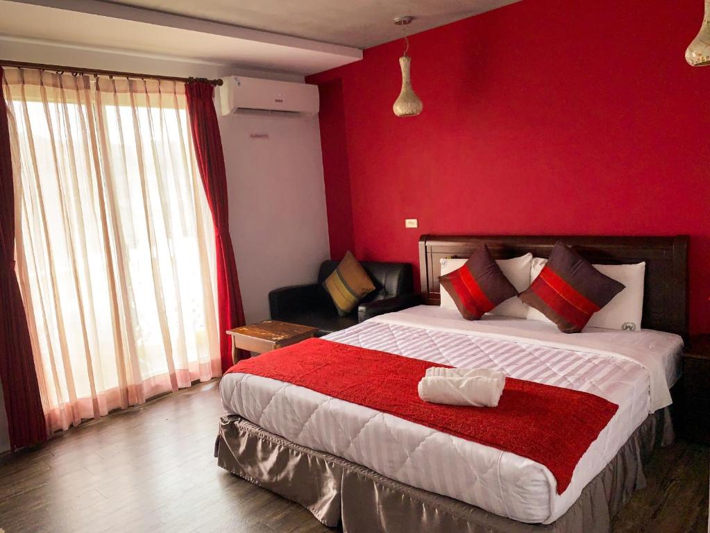 1 dormitorio con 1 cama grande y pared roja en Xing Ji Hotel, en Kenting