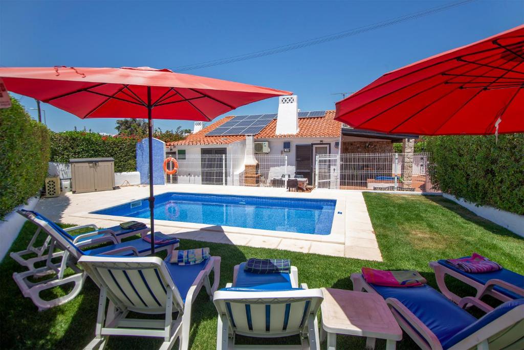 un gruppo di sedie e ombrelloni accanto alla piscina di LOTUS VILLA, Albufeira ad Albufeira