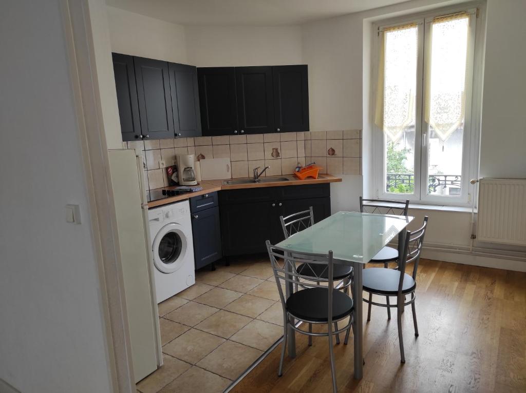 eine Küche mit einem Tisch und Stühlen sowie einer Waschmaschine in der Unterkunft Superbe F3 dans résidence calme, in Nancy