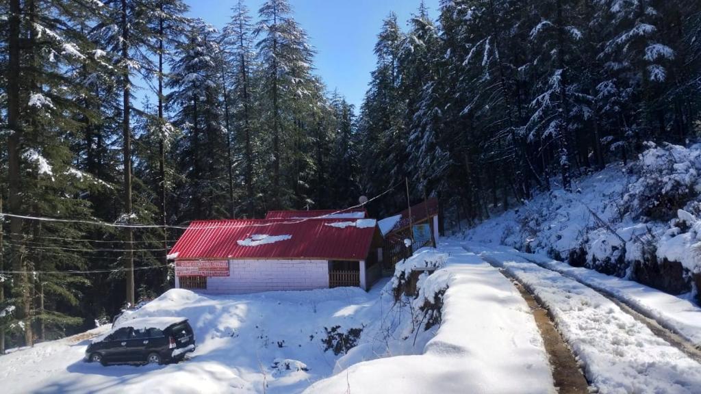 a truck parked in the snow next to a building at cedar tree cottage gadakufri in Matiāna