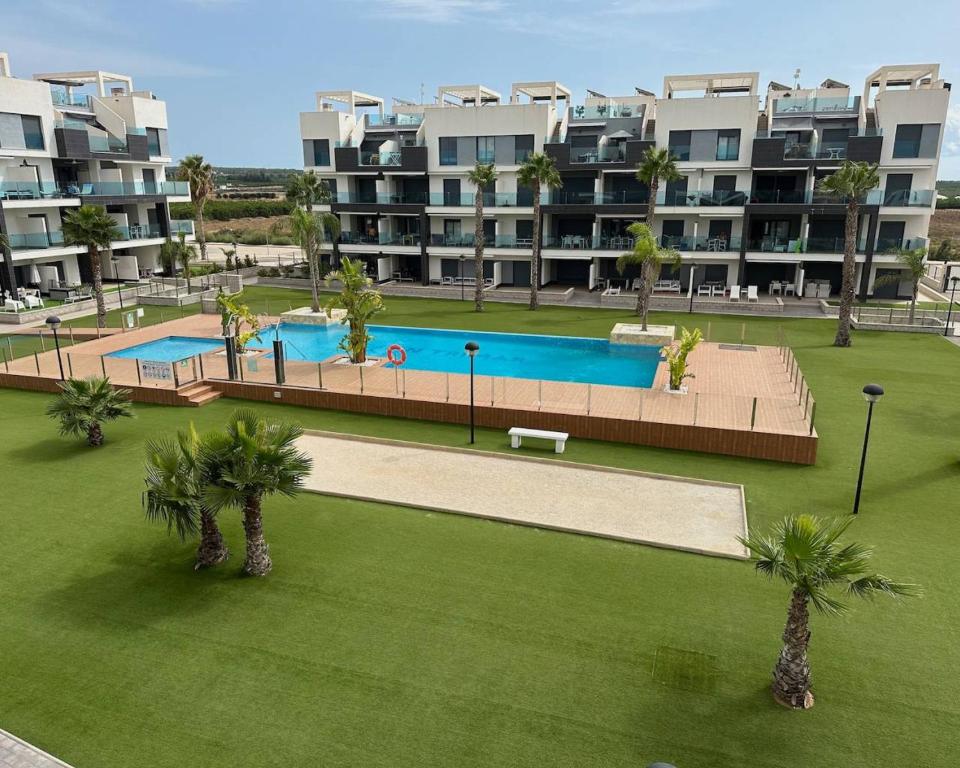 an apartment complex with a swimming pool and palm trees at Oasis Beach 13 Casa del Guardamar in Alicante