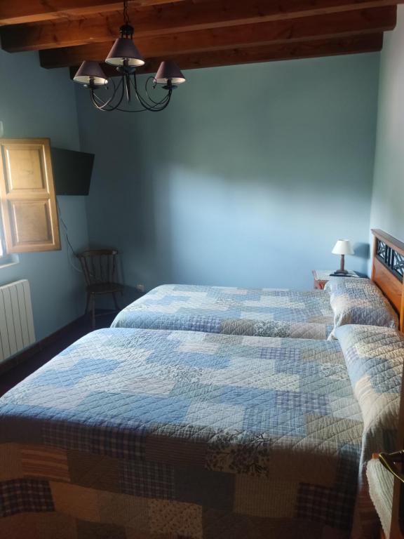 two beds in a room with blue walls at Casa Rural Juaco in Bimenes