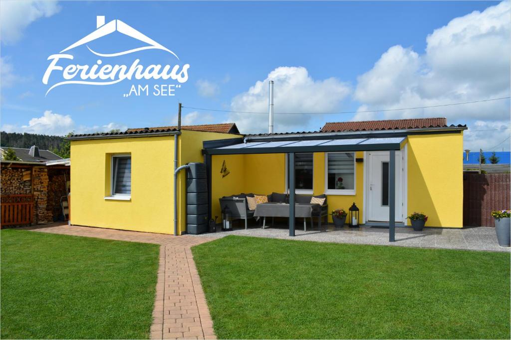 a yellow tiny house with a patio in a yard at Ferienwohnung am See in Heldrungen