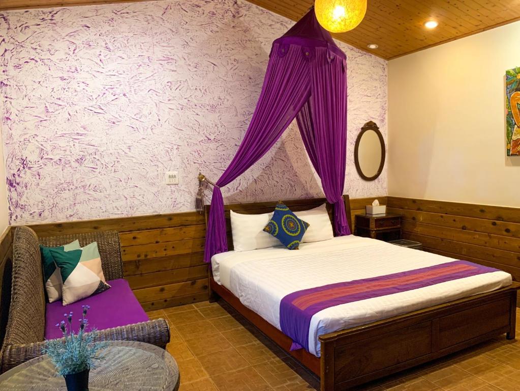 una camera con letto a baldacchino viola di Xing Ji Bungalow a Kenting
