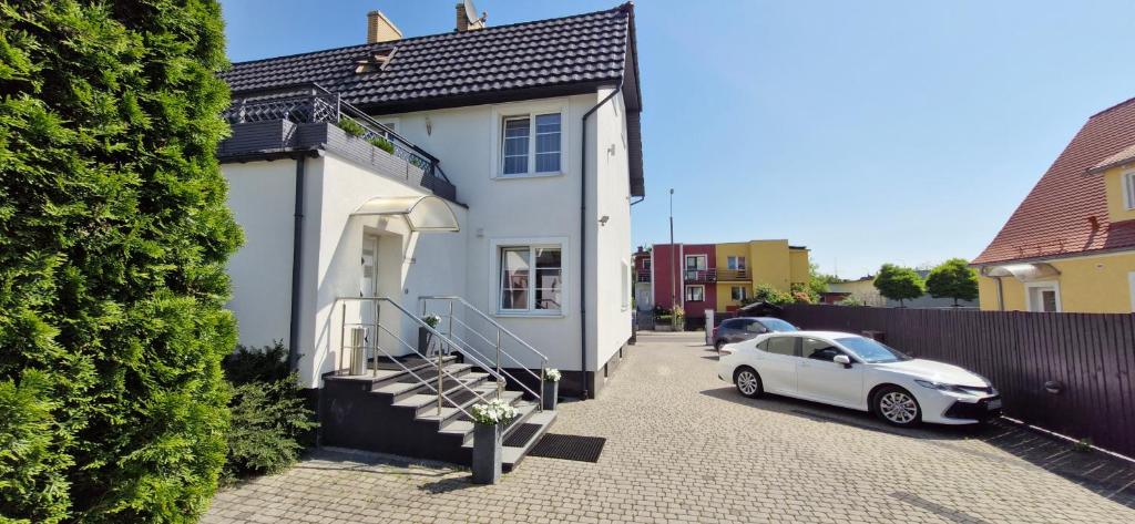 a white car parked in front of a white house at Villa Stratus in Gdańsk