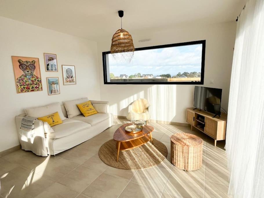 a living room with a white couch and a tv at Villa Molène jacuzzi et plage à 500 m in Tréveneuc