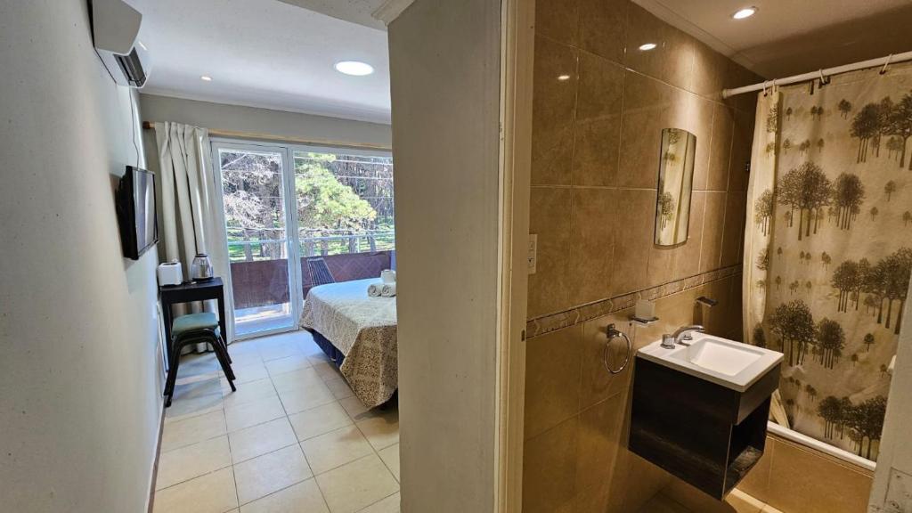 baño con lavabo, cama y ventana en Hotel Firenze en Necochea