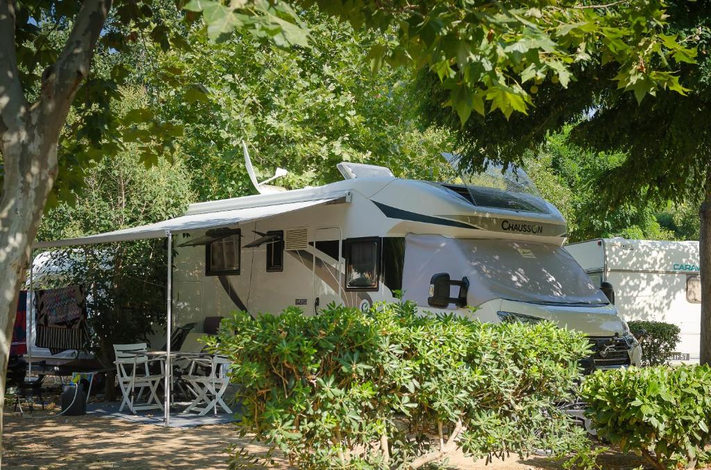 a white rv with a tent and tables and chairs at Camping La Plage Argelès in Argelès-sur-Mer