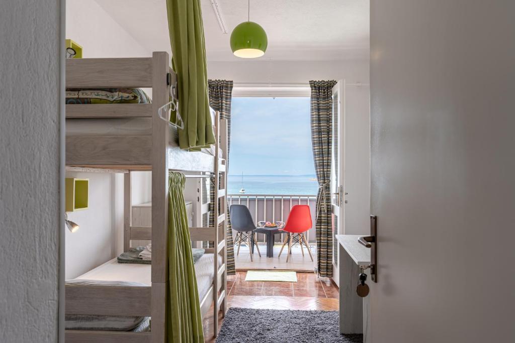 een slaapkamer met een stapelbed en uitzicht op de oceaan bij Hostel Casa La Cha in Novalja