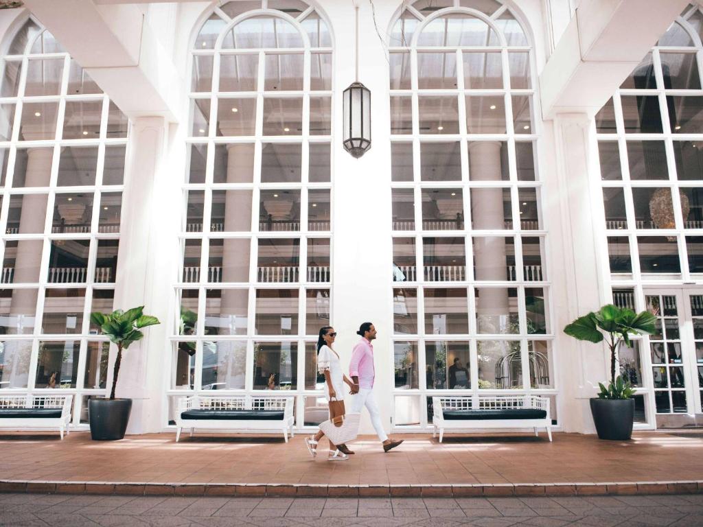 2 personnes marchant devant un bâtiment avec fenêtres dans l'établissement Pullman Cairns International, à Cairns