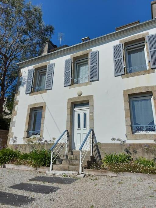 une maison blanche avec des escaliers en face de celle-ci dans l'établissement Maison familiale bretonne à 2 pas de la mer et des commerces, à Carantec