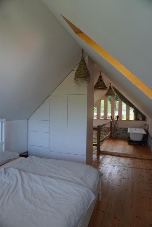 a bedroom with a white bed and a staircase at Stodola Počúvadlo in Počúvadlo