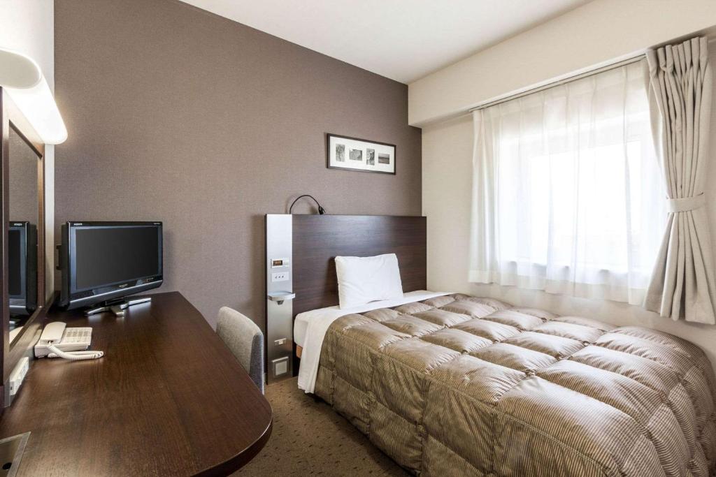 帯広市にあるコンフォートホテル帯広のベッド、デスク、テレビが備わるホテルルームです。