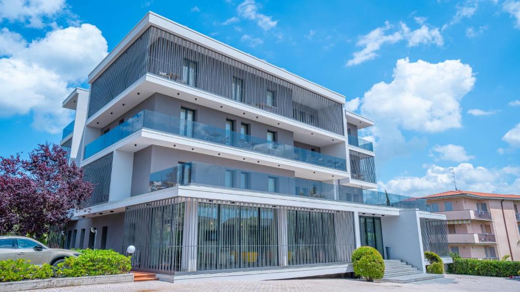 an apartment building with balconies and a car parked in front at Hotel Bella Peschiera in Peschiera del Garda