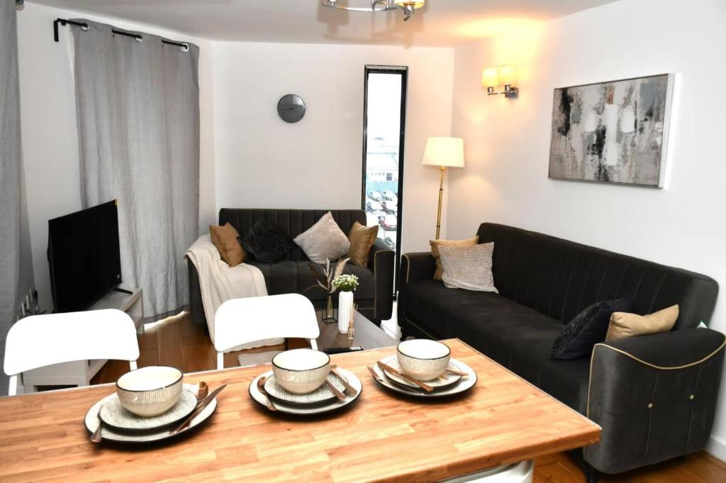 a living room with a black couch and a table at Sleeps 4 - Private Balcony - Wheelchair Accessible in London
