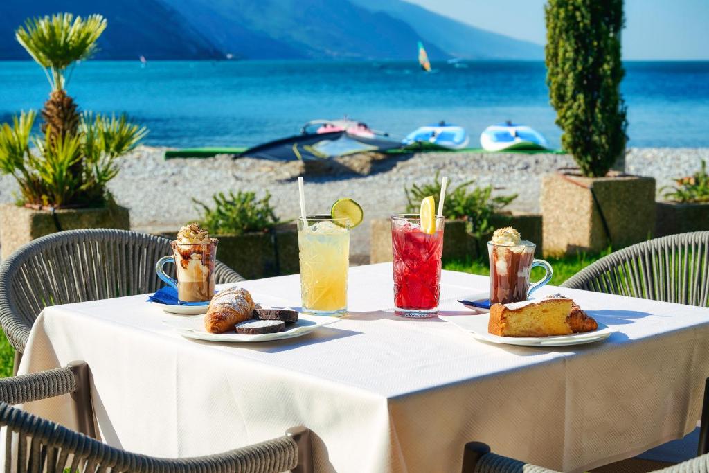 un tavolo con cibo sopra con vista sull'oceano di Hotel Lido Blu - Surf & Bike a Torbole