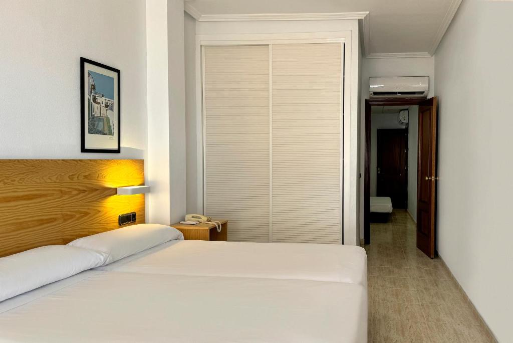 a bedroom with a white bed and a window at Hotel Don Ignacio in San José
