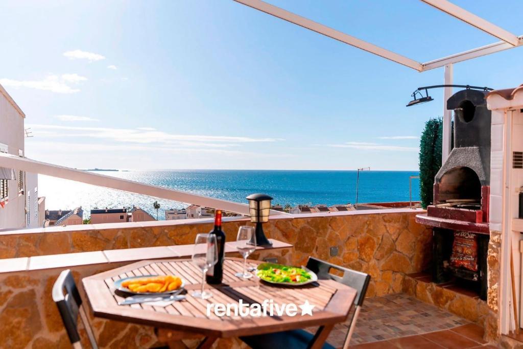 uma mesa com uma garrafa de vinho numa varanda com o oceano em rentafive Vistas al mar Bungalow BBQ em Santa Pola
