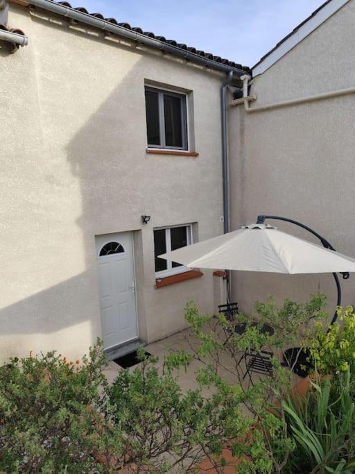 - un bâtiment blanc avec une porte et un parasol dans l'établissement Maisonnette à 5 minutes d'Albi, à Carlus