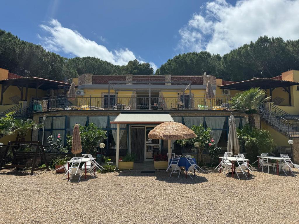 een hotel met tafels en parasols ervoor bij Hotel Paradiso in Tarquinia