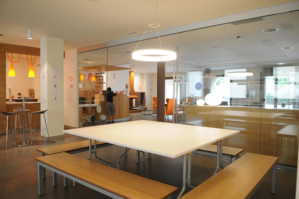 a dining room with a white table and benches at Albergue Guiana in Ponferrada