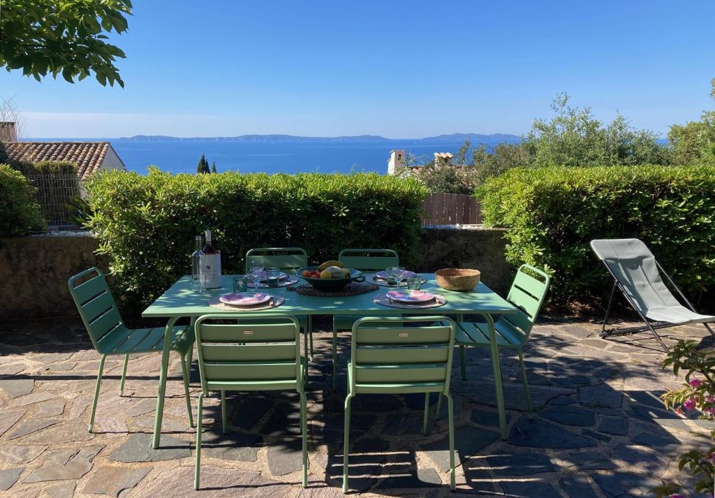 - une table avec des chaises vertes et une table avec de la nourriture dans l'établissement Beautiful sea view, AC, garden, beach minutes away by foot!, à Rayol-Canadel-sur-Mer