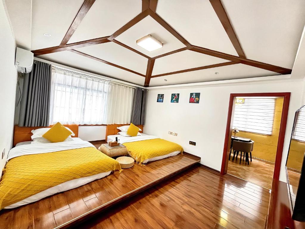 two beds in a hotel room with yellow sheets at Yijingju Humanistic Inn in Zhangjiajie
