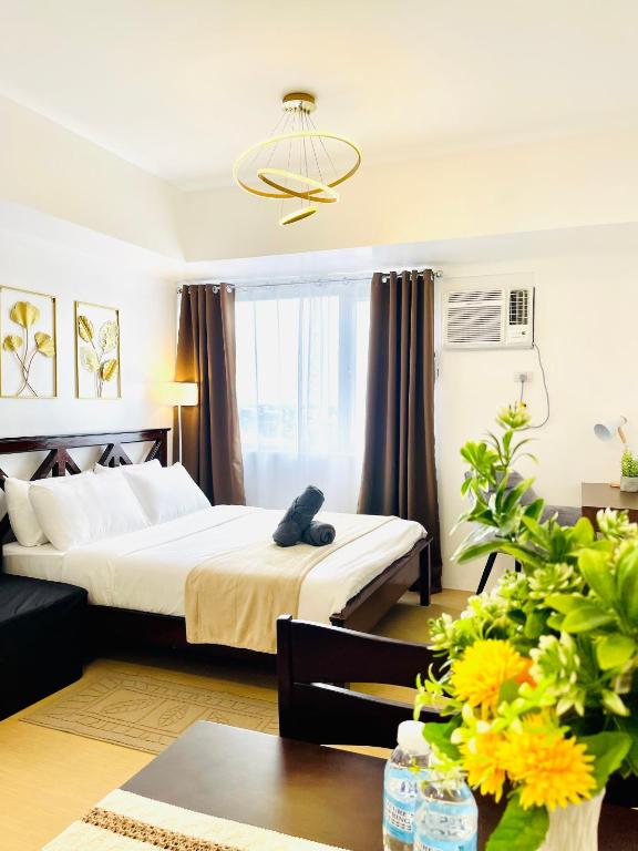 a hotel room with a bed and a table with flowers at Spacious Stylish Studio Unit at Avida Aspira Tower 1 in Cagayan de Oro