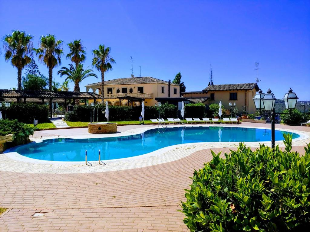 una piscina frente a una casa con palmeras en Tenuta Bellaprima CALTAGIRONE, en Niscemi