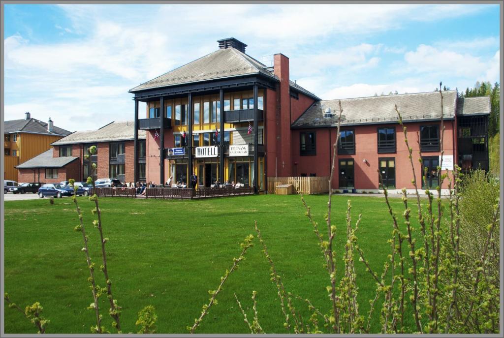 a large red brick building with a green lawn in front at Trudvang Apartment Hotel in Rena
