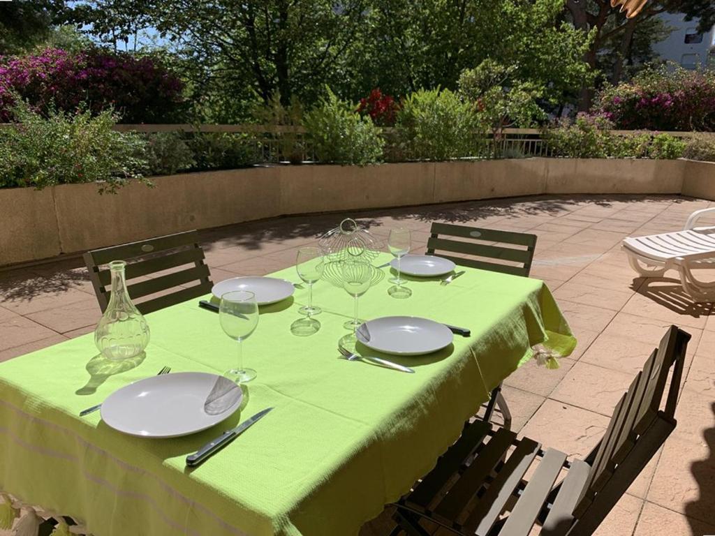 uma mesa com uma toalha de mesa verde, pratos e copos de vinho em Appartement Hyères, 2 pièces, 4 personnes - FR-1-335-184 em Hyères