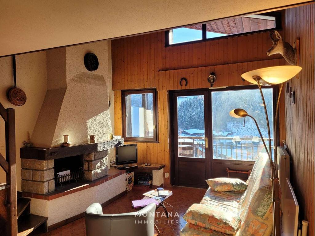 un salon avec un canapé et une cheminée dans l'établissement Grand T3 + mezzanine pour 6 pers, balcon exposé Sud - FR-1-458-192, au Grand-Bornand
