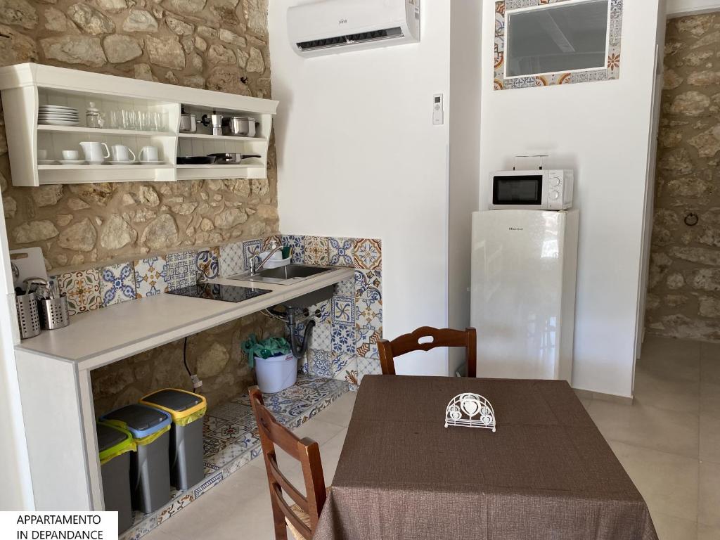 a small kitchen with a table and a refrigerator at Tenute Plaia Agriturismo in Scopello