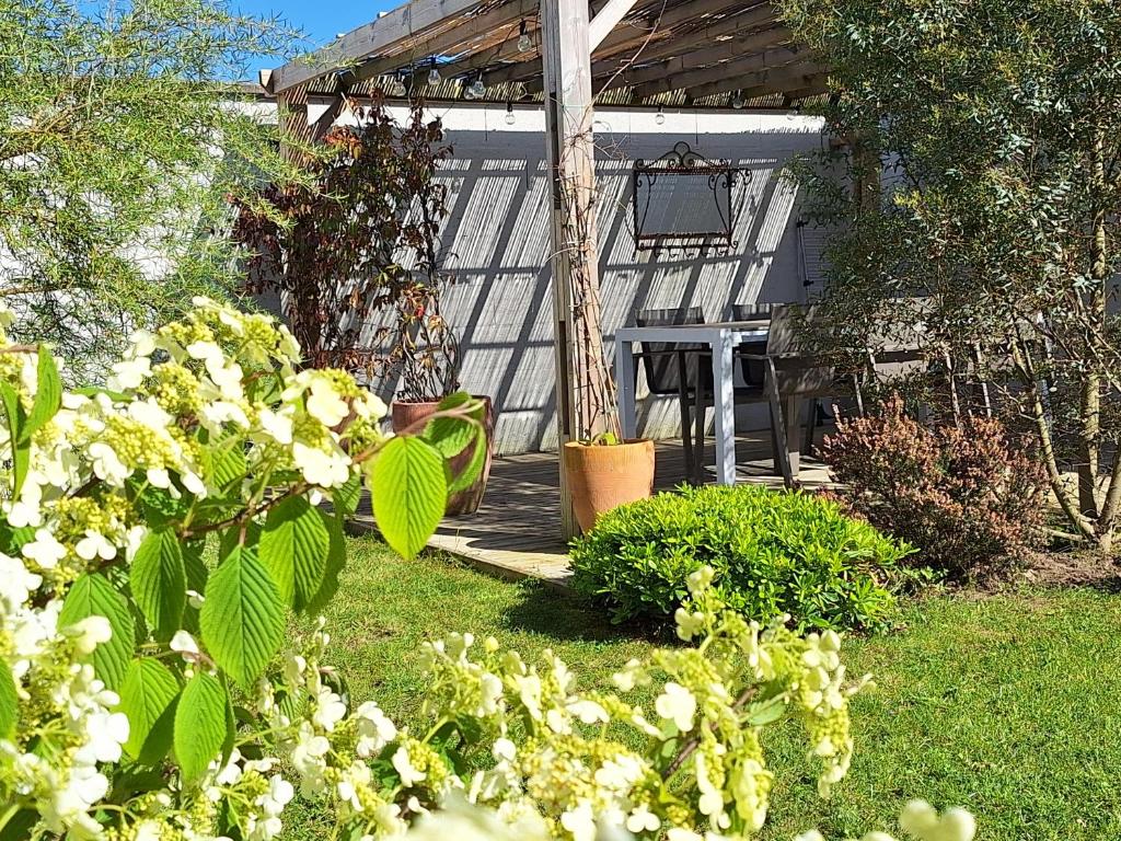 um jardim com uma pérgola e algumas plantas e flores em Planchesdisa em Saint-Pair-sur-Mer