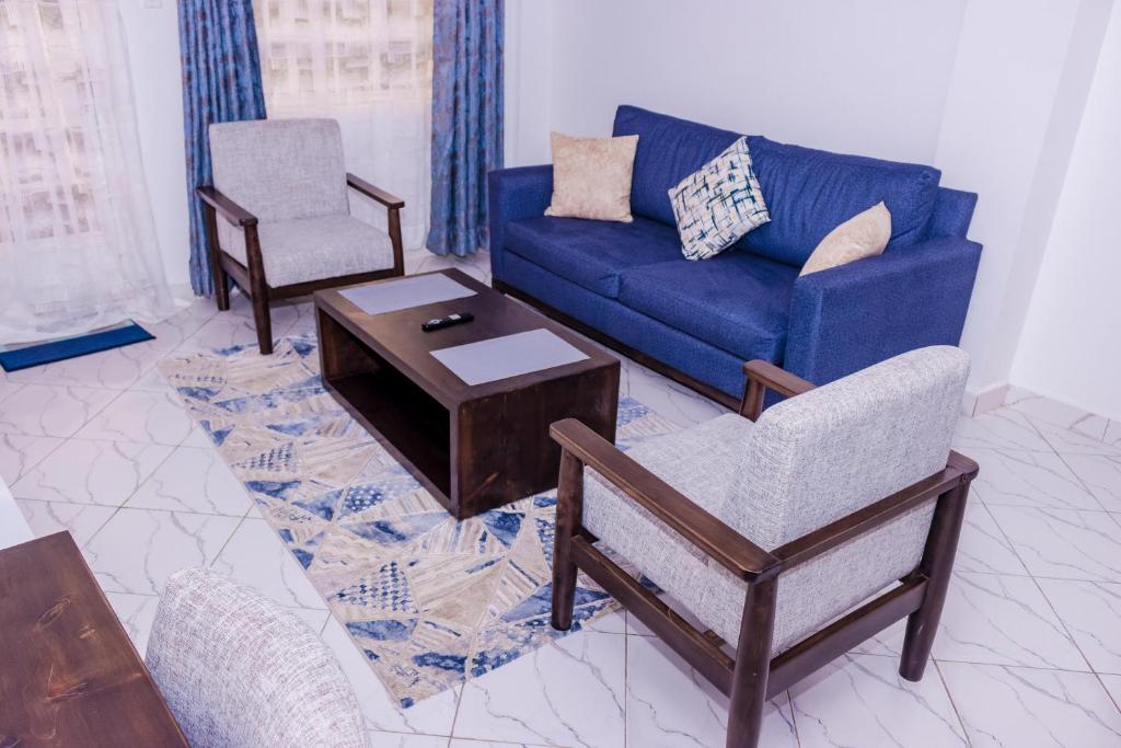 a living room with a blue couch and a chair at The pine 1 bedroom house California plaza in Nanyuki