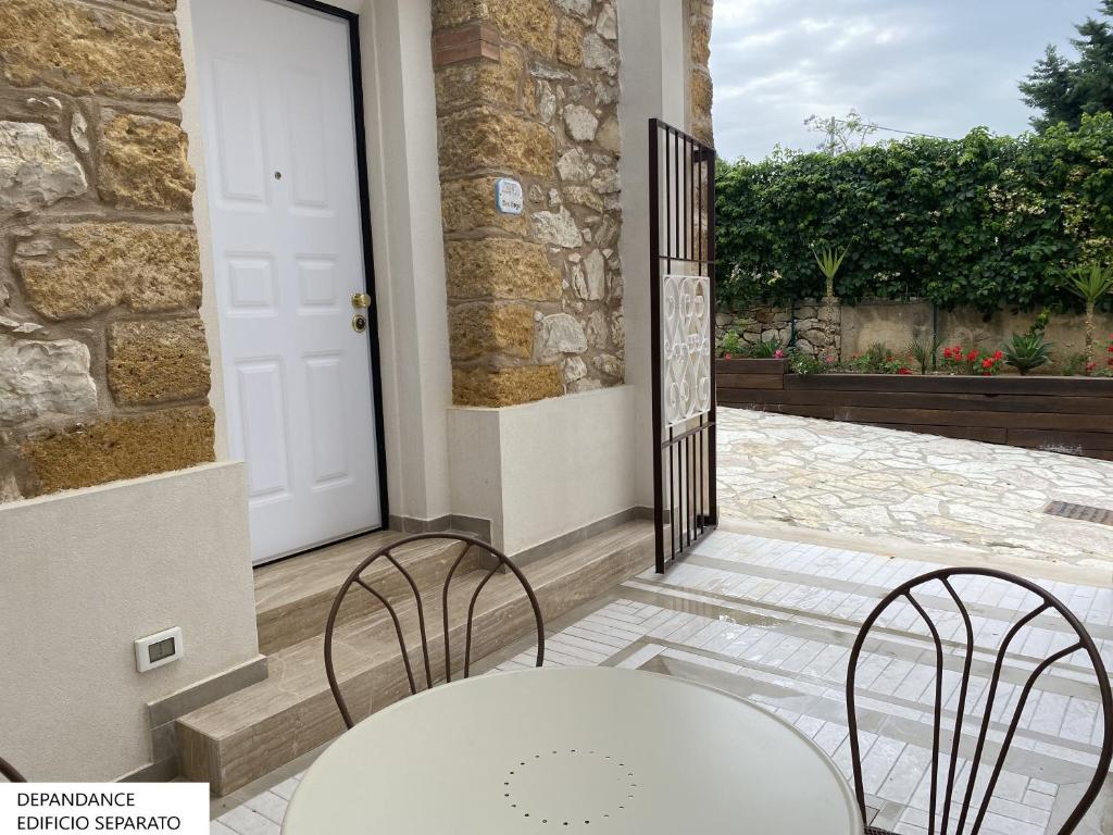 a patio with a white table and chairs and a door at Tenute Plaia Agriturismo in Scopello
