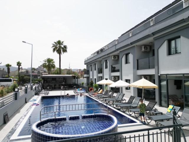 a swimming pool with chairs and umbrellas next to a building at Ozturk Apart Hotel in Marmaris