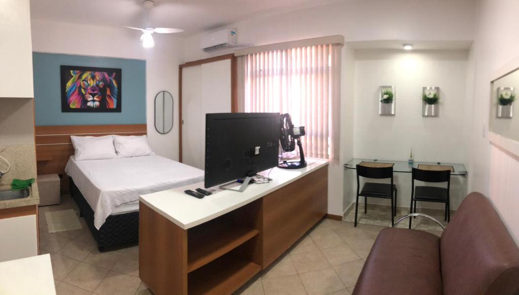 ein Hotelzimmer mit einem Bett und einem Schreibtisch mit einem TV in der Unterkunft Flat Luxo 5* centro: Seu Sonho esta aqui! in Brasilia