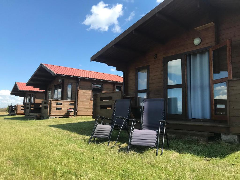 a group of chairs in front of a log cabin at Domki na Wzgórzu in Ryn