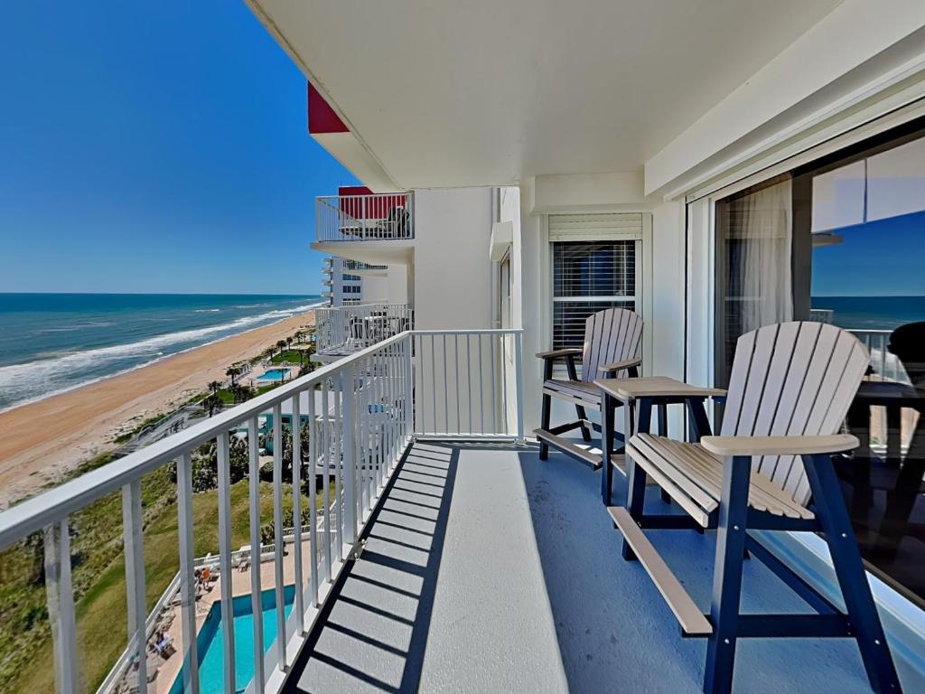 a balcony with chairs and a view of the beach at Sea Winds 904 in Ormond Beach