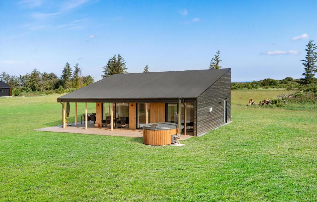 ein Haus mit einem schwarzen Dach auf einem grünen Feld in der Unterkunft Stunning Home In Hjørring With Wifi in Hjørring