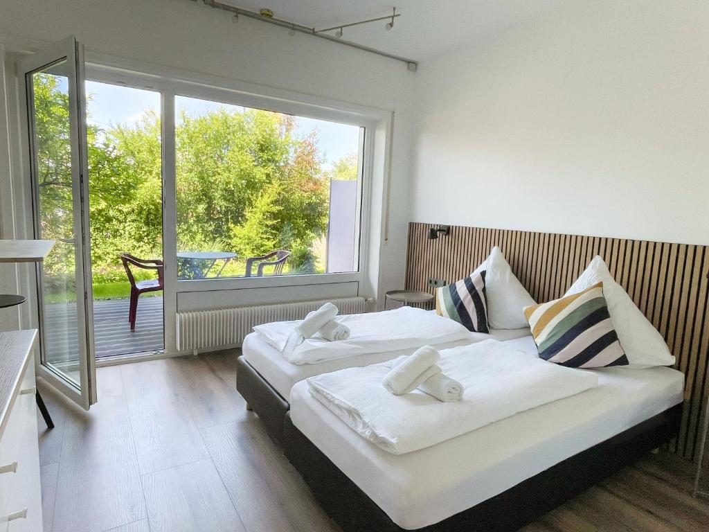 a bedroom with two beds and a large window at Hotel Buchberg - Moderne Design-Apartments in Bermatingen