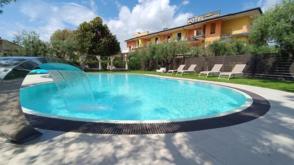 a pool with a fountain in front of a building at Hotel Confine in Colà di Lazise