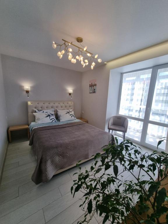 a bedroom with a large bed and a chandelier at Затишні апартаменти вул Глибока 24 in Ternopilʼ